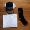 White shirt, black and red socks and a trail cap in grey and black on a wooden table