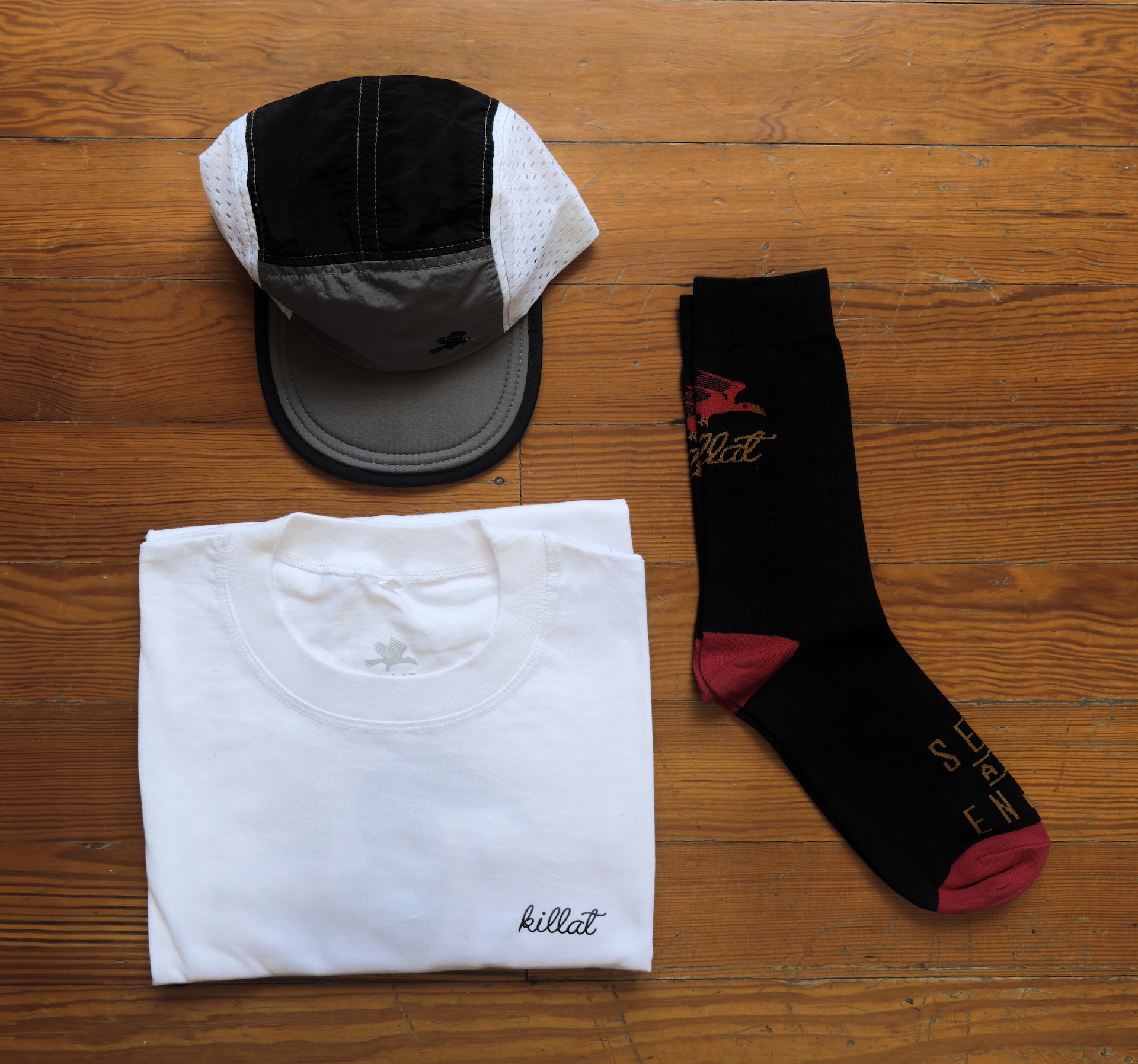White shirt, black and red socks and a trail cap in grey and black on a wooden table