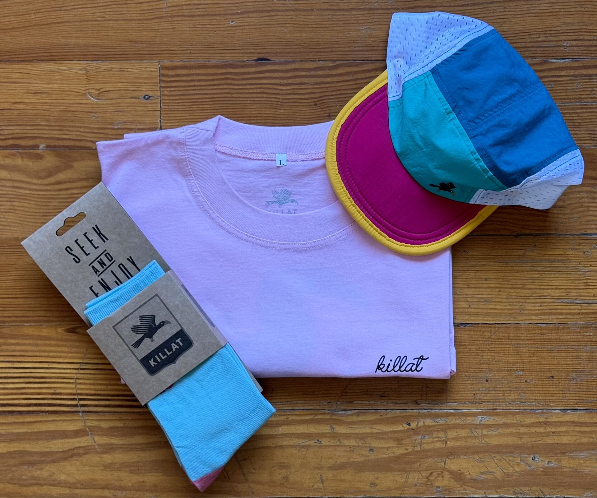 Cap, pink shirt and teal socks on wooden floor