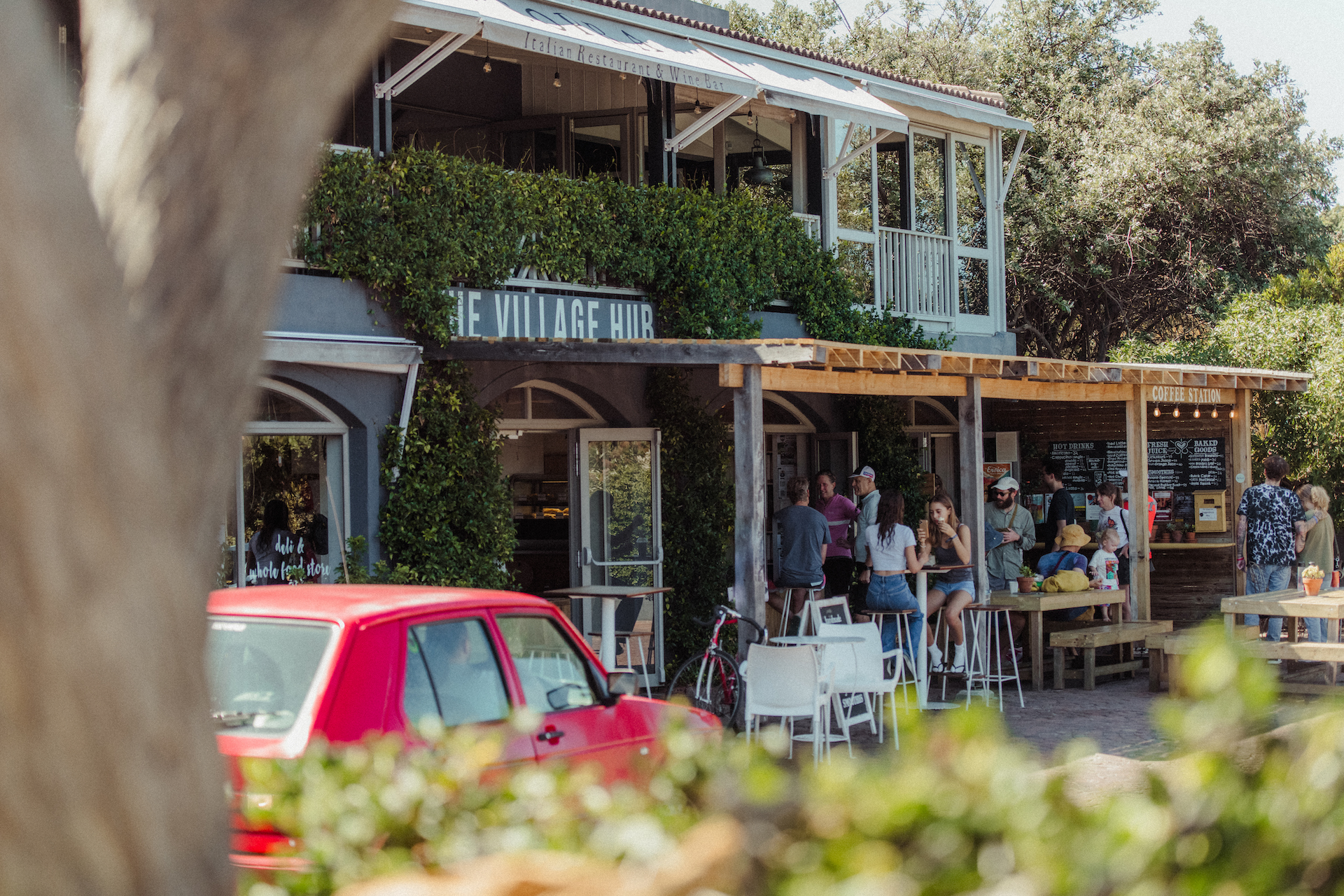 Crowd at coffee shop outside with red volkswagen and vintage bike